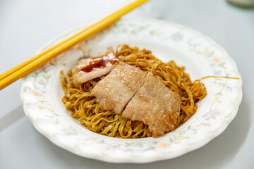 Macau-style pork chop with dry noodles, drizzled with oyster sauce, served on a decorative plate, highlighting the tender pork and flavorful noodles