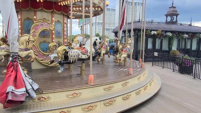 Carousel with beautiful horses is spinning. City attraction against the backdrop of beautiful house. Horizontal video 4k.