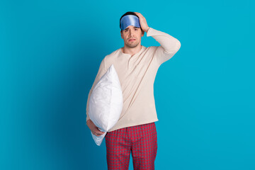 Portrait of nice young man hold pillow wear pajama isolated on blue color background