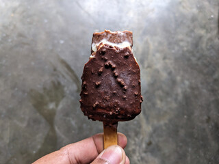 Chocolate and almond ice cream on hand after bite. Holding bitten chocolate popsicle. eating chocolate ice cream. Popsicle ice cream.