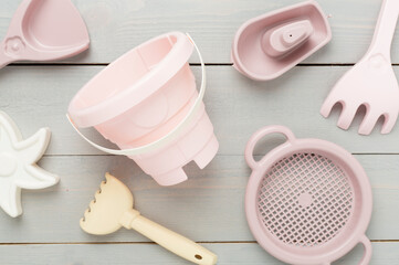 Cute toys for playing with sand on wooden background, top view