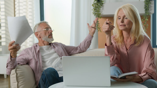 Upset retired mature Caucasian woman man couple senior elderly male female arguing worrying laptop problem online banking loss error wife husband family quarrel losing money bankruptcy conflict home