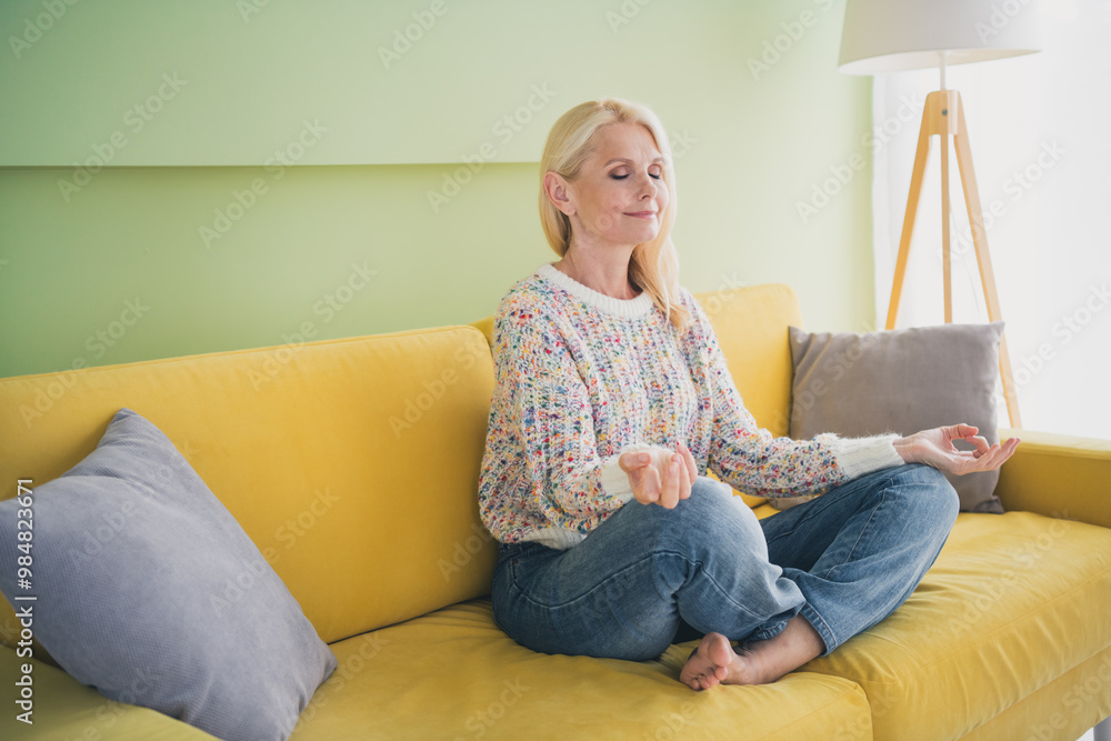 Poster full length portrait of nice aged lady sit sofa meditate living room flat indoors