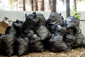 large black garbage bags near fence, waste disposal, landfill