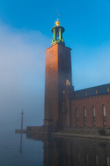 Stockholm city hall, in the morning fog, early autumn, majestic tower with morning sunlight and...