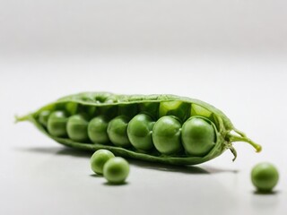 A single, open green pea pod with a few peas still inside, displayed on a plain white surface, showcasing its simple, natural beauty.