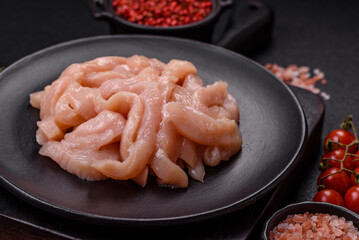 Raw chicken fillet cut into strips with spices and herbs