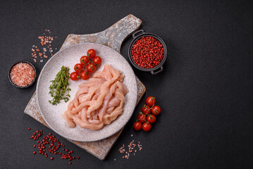 Raw chicken fillet cut into strips with spices and herbs