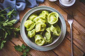 Green dumplings with meat. Dumplings with spinach in a plate on a wooden table. Close-up.