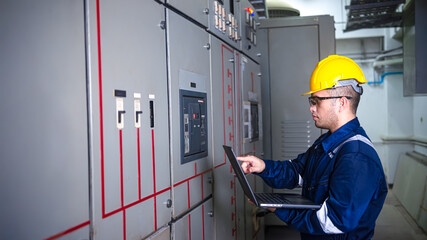 Electrical engineer check the operation of the main electrical control panels and switches, record values ​​on tablets, electrician inspect the electrical systems in the factory.