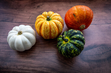 Still life of pumpkins or Winter squash in various colours with a wooden background.