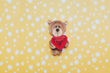 Colorful paper bear with heart on yellow background with stars. Hand made of paper quilling technique. paper card for valentine's day teddy bear with a heart in its paws.