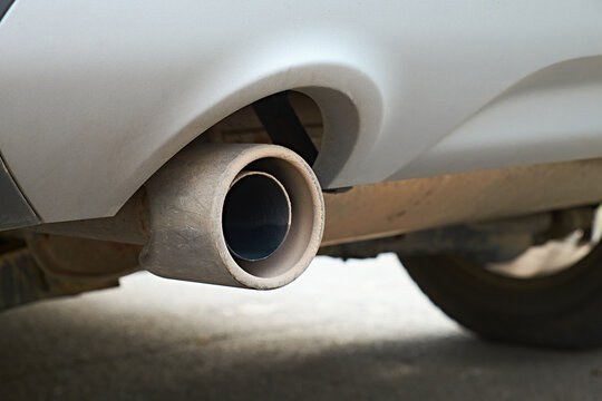 Close-up view of a car exhaust pipe and rear tire. The image emphasizes the vehicle's mechanical components, suitable for topics related to automotive care, emissions, and maintenance.