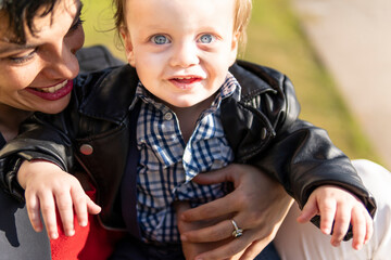 Portrait of blue-eyed blonde baby in the park with his mother