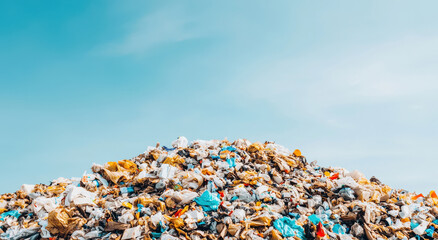 A large mound of mixed plastic waste under a clear blue sky, highlighting the issue of pollution and waste management.