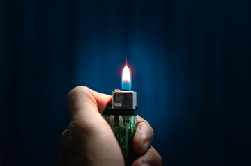 A hand is holding and lighting a lighter