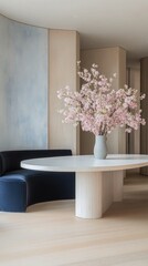 This dining room embodies minimalist wabi-sabi style with a calming light blue mural, a chic white table, and a pink magnolia in a sleek vase, offering a tranquil eating space