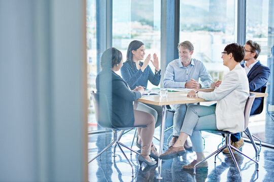 People, meeting and feedback in office for business, marketing strategy and finance management. Corporate team, woman speaker and discussion at table with report, paper or planning for upcoming audit