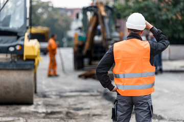 Construction workers assessing road work progress at a job site during the day