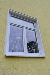 A skeleton looks out the window.
