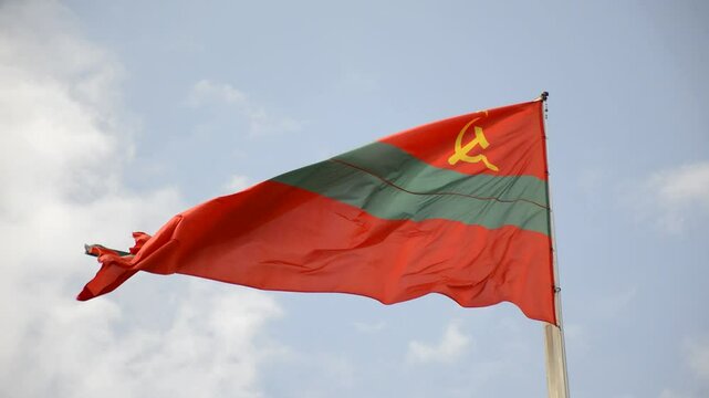 The state flag of the Pridnestrovian Moldavian Republic flutters in the wind in the cloudy sky. High quality fabric. International relations concept. symbol of statehood