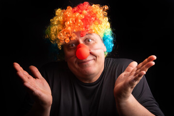 Adult man with wig and clown nose, selective focus, dark background.