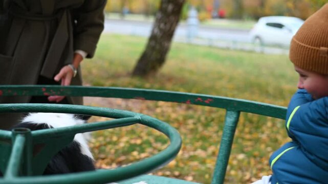 mother with disabled child in disabled Kremlin walk in autumn on the playground on the carousel. High quality FullHD footage