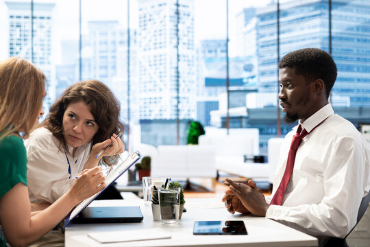 Team of employers conducting interview with man to determine their suitability for company position. HR department colleagues reviewing resume to determine if necessary qualifications are met