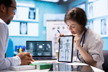 Medical expert explaining the human anatomy to patient in cabinet, presenting the diagnostic...