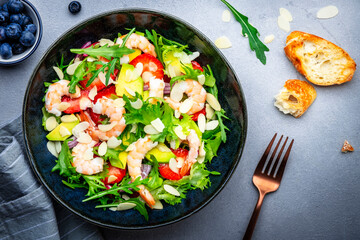 Shrimp salad with strawberries, onions, lettuce and almonds, gray background, top view