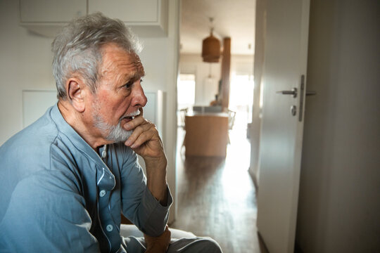 Worried senior Caucasian man sitting alone at home, deep in thought