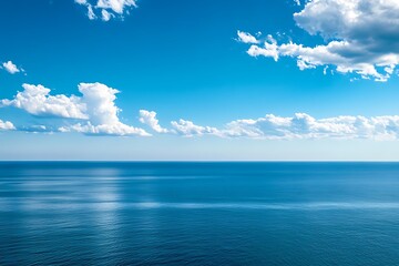 Obraz premium Calm blue ocean water with fluffy clouds in the sky