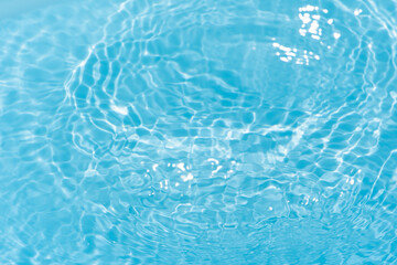 Blue water with ripples on the surface. Defocus blurred transparent blue colored clear calm water surface texture with splashes and bubbles. Water waves with shining pattern texture background.