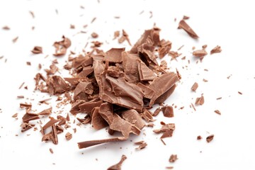 Fototapeta premium Close-up of milk chocolate shavings on white background. Shavings thin, rough, irregular in shape, with rich brown color characteristic of high-quality cocoa. Confection made from natural