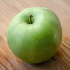 A single Earligold apple on a wooden surface