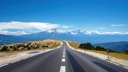 Narrow highway leads to iconic Mont Ventoux mountain in France. Blue sky with clouds in background. Scenic road winds up to summit. Provence landscape with rocky terrain.