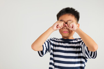 Asian kid boy emotional turmoil unfolds as cries and wipes tears away with fingers. Isolated on white background, primary child expressive face paints vivid picture of sadness and frustration