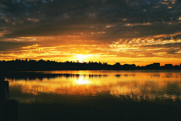 Obraz premium The evening sun turns the beautiful Dows Lake into burnished gold during a fiery twilight sunset on a warm fall evening at Ottawa,Ontario,Canada 