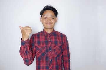 portrait of a handsome Indonesian man having a random expression wearing a checkered red flannel...