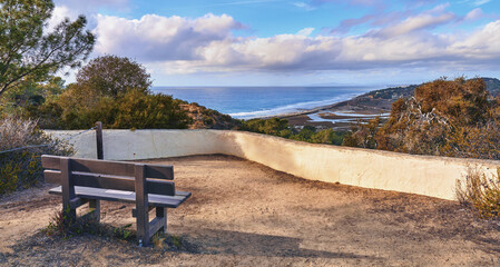 Park, outdoor bench and landscape of beach for travel location, holiday destination and scenery of ocean. Nature, horizon and blue sky for adventure, hiking and sightseeing view of sea in California