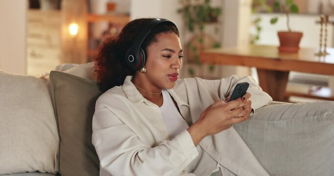 Headphones, cellphone and woman on sofa in home listening to music, podcast or playlist for blog review. Relax, phone and female freelance critic with audio tech for streaming new album at apartment.