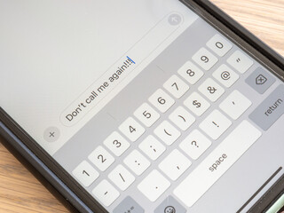 A heated text message is typed on a smartphone, expressing anger and frustration with exclamation marks.