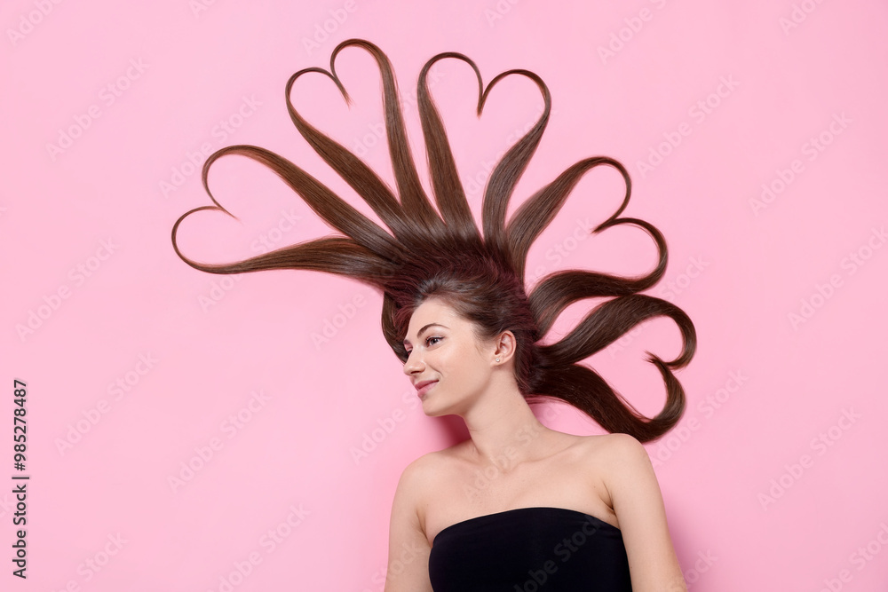 Poster Beautiful young woman with hair in shape of hearts on pink background, top view