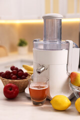 Modern juicer, fresh fruits and glass on white marble table in kitchen