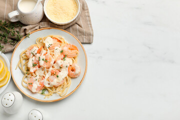 Tasty pasta with shrimps, creamy sauce and cheese served on white marble table, flat lay. Space for text