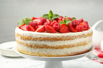 Tasty sponge cake with fresh berries and mint on white table, closeup
