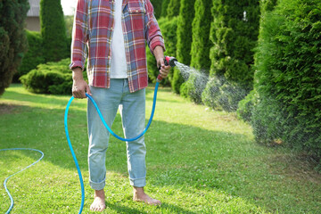 Man watering lawn with hose in backyard, closeup
