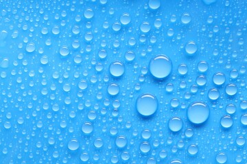 Water drops on blue background, top view