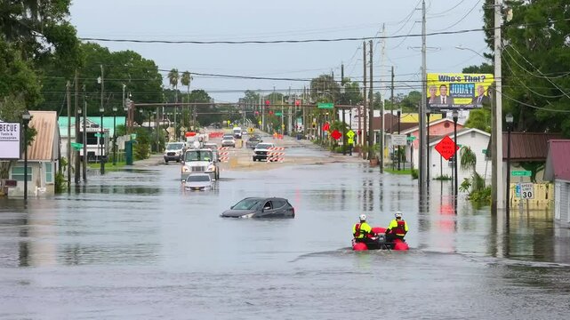 Emergency service rescue personnel on flooded road with sunken cars in surrounded with water Florida residential area. Consequences of hurricane Debby natural disaster