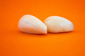 two cloves of garlic with an orange background